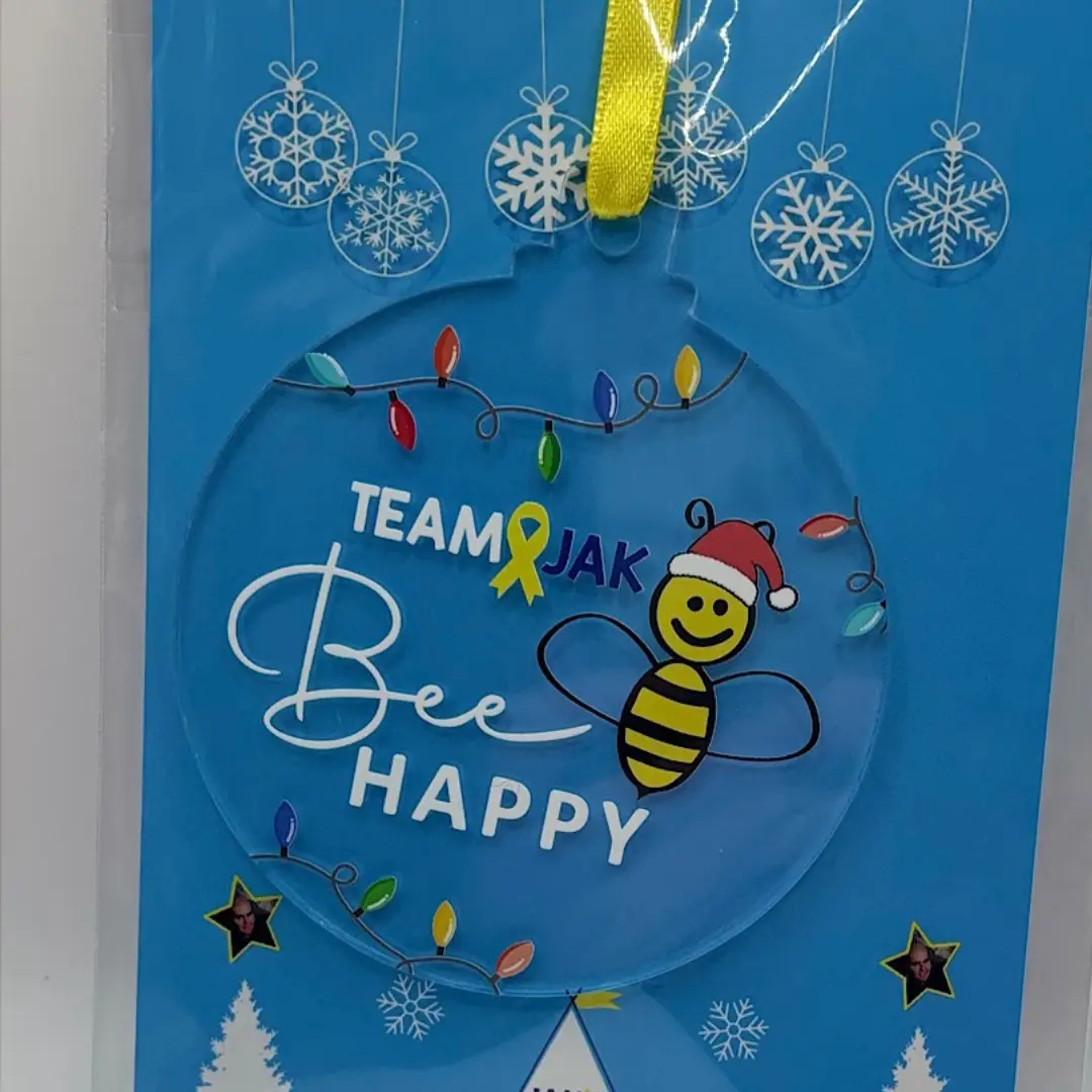 Team Jak's Bee Happy Christmas Bauble, features the uplifting Bee Happy motif with a Santa hat and colourful fairy lights.